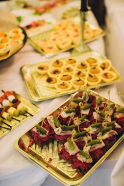Yemek büfesi çeşitli lezzetli aperatifler, kanepeler ve aperatifler sunuyor. Altın tepsiler üzerine dizilmiş, bir etkinlik için mükemmel.