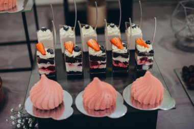 Çikolata katmanları, krema, taze çilek ve açık büfedeki pembe kremanın yer aldığı çeşitli tatlı tatlılar.