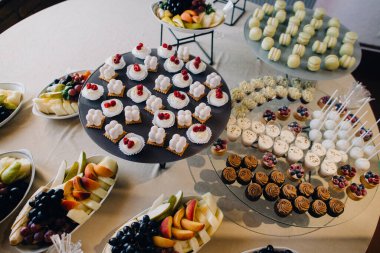 Bir etkinlik için renkli tatlı çeşitleri, mini pastalar, kekler ve taze meyve tabakları sunan tatlı büfesi.