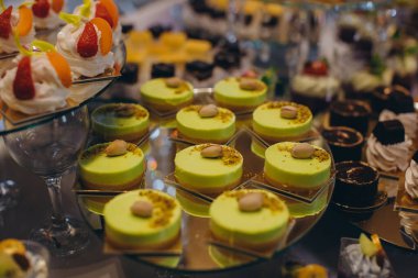 Canlı şam fıstıklı mus kekleri, meyveli taze kremalı tatlılar ve şenlikli bir büfede çeşitli tatlı şeyler.