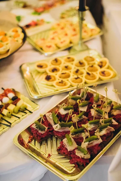 Yemek büfesi çeşitli lezzetli aperatifler, kanepeler ve aperatifler sunuyor. Altın tepsiler üzerine dizilmiş, bir etkinlik için mükemmel.