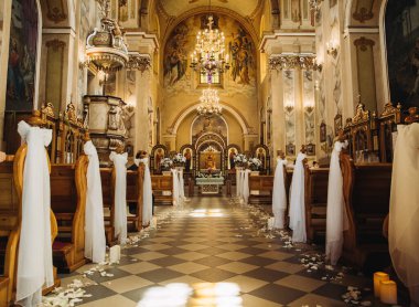 Hıristiyan kilisesinin içini kilise sıraları, beyaz perdeler, gül yaprakları ve düğün için mumlarla süsleyin.