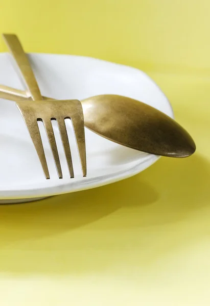 Colher e garfo no prato branco — Fotografia de Stock