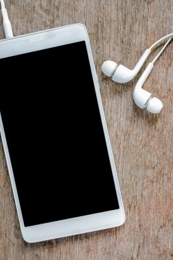 Ahşap arka plan üzerinde kulaklık ile beyaz smartphone