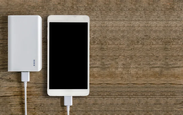 Banka ahşap arka plan üzerinde beyaz smartphone ve güç