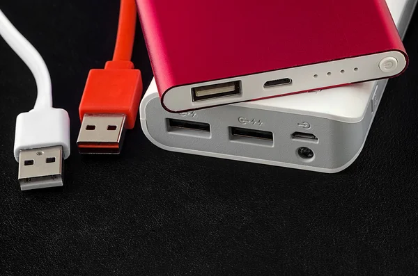 Красно-белый банк питания с USB-кабелем на черной кожаной подставке — стоковое фото