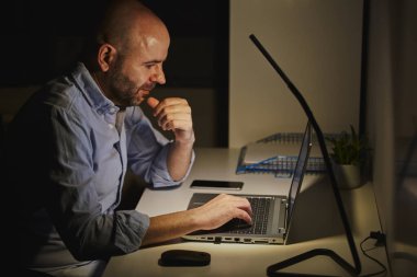 Evde dizüstü bilgisayarla çalışan serbest meslek sahibi bir girişimci. Yetişkin kel adam.