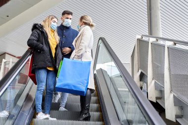 Yeni alışveriş normalliği. Maskeyle alışveriş yapan üç arkadaşın yatay portresi. Coronavirus konsepti. Salgın döneminde alışveriş kavramı.