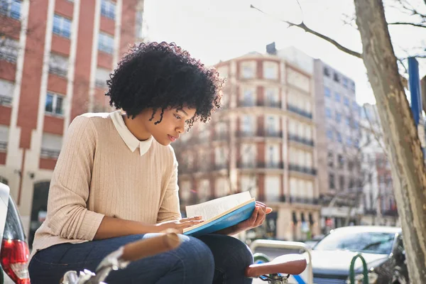 Bankta oturmuş kitap okuyan Afro-Amerikalı bir kadın. Kitaplı Latin bir kadın.. 