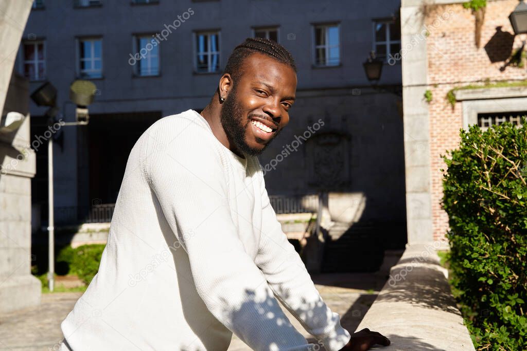 Young African American man smiling leaning against a wall, Happy Latino man. 