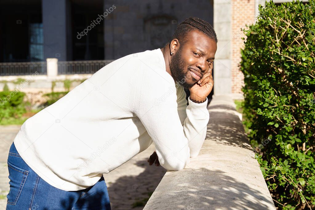 Young African American man smiling leaning against a wall, Happy Latino man. 