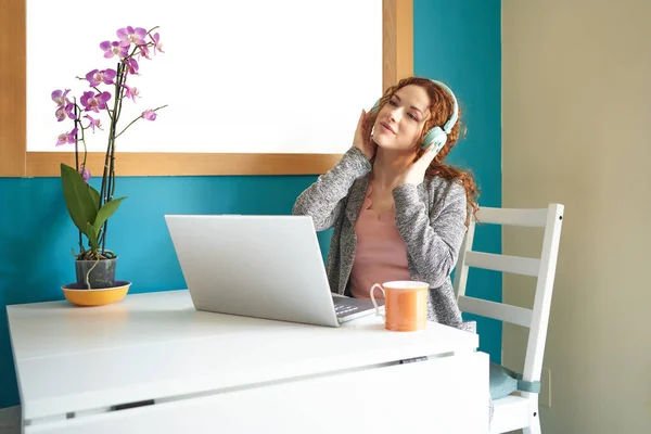 Mujer joven con auriculares sentados en el escritorio en el interior de la oficina en casa. —  Fotos de Stock