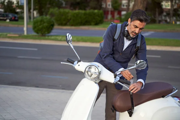Pria dewasa membuka kunci keamanan pada skuter putihnya. Konsep perlindungan anti-pencurian. — Stok Foto