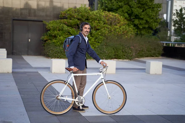 Pebisnis berjenggot, tampan dan percaya diri, membawa ransel, berjalan keluar dengan sepeda. Konsep transportasi ramah lingkungan. — Stok Foto