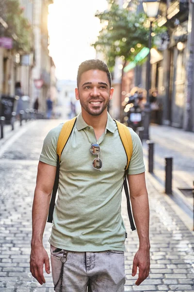 Jovem sorridente latino caminhando pelas ruas da cidade. Homem latino de jeans e camisa de pólo verde. — Fotografia de Stock