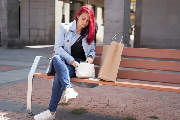 ショッピングの後、広場のベンチに座って青いトレンチコートの赤い髪の女性. — ストック写真