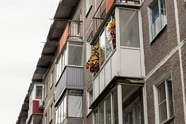 Houseplants stand on the balcony of an old five-story building in the Russian province.