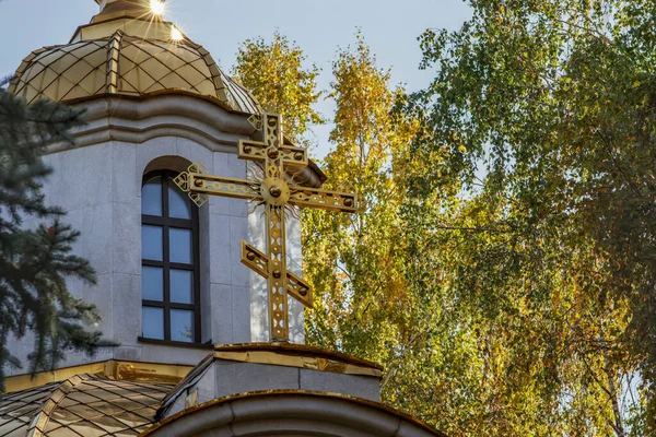 Beautiful golden cross and dome on a Christian Russian church on a sunny autumn day. Religion and culture of Russia.