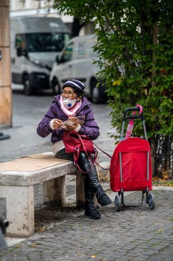 Terni, itali Kasım 05 2020: tıbbi maskeli yaşlı bir kadın telefonda bankta oturuyor.