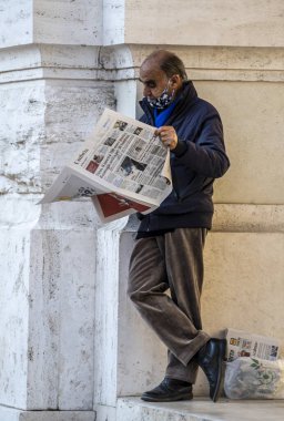 Terni, İtalya Kasım 06 2020: Gazete okuyan bir binaya yaslanan adam