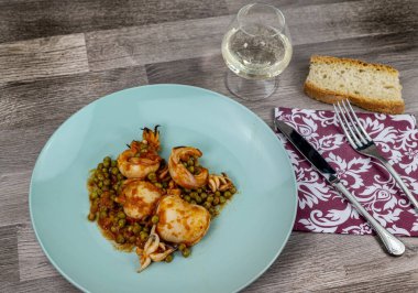 Düz kompozisyon mürekkep balığı ve bir bardak şarap ve ekmek ile bezelye.