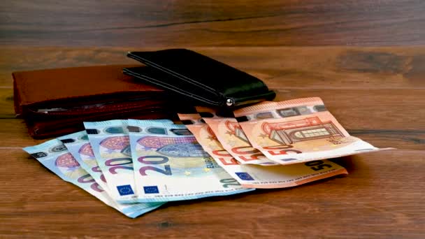 Holztisch mit Euro-Banknoten und verschiedenen Geldbörsen