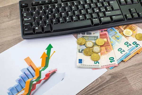 euro money of different denominations and computer keyboard and graph on wooden background