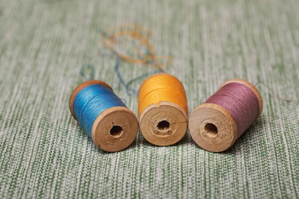 Three vintage wooden spools with old threads from grandma\'s box. Materials for creativity and needlework.