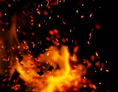 Siyah arkaplanda kıvılcımlar saçan bir ateş alevi