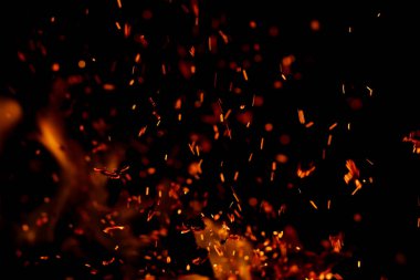 Siyah arkaplanda kıvılcımlar saçan bir ateş alevi