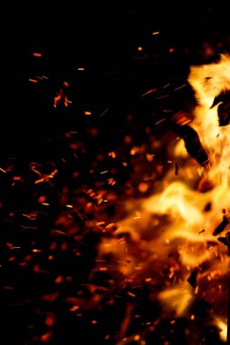 Siyah arkaplanda kıvılcımlar saçan bir ateş alevi