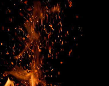Siyah arkaplanda kıvılcımlar saçan bir ateş alevi