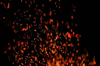 Siyah arkaplanda kıvılcımlar saçan bir ateş alevi