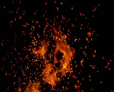 Siyah arkaplanda kıvılcımlar saçan bir ateş alevi