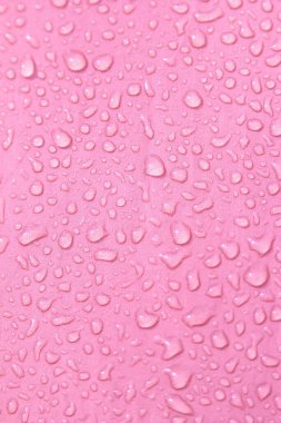 Pembe arka planda saydam su damlaları
