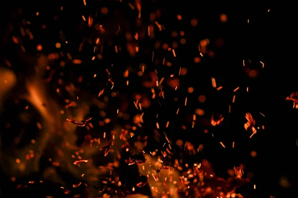 Siyah arkaplanda kıvılcımlar saçan bir ateş alevi