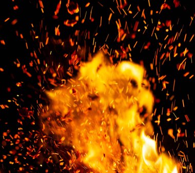 Siyah arkaplanda kıvılcımlar saçan bir ateş alevi