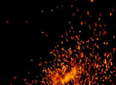 Siyah arkaplanda kıvılcımlar saçan bir ateş alevi