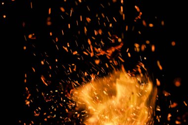 Siyah arkaplanda kıvılcımlar saçan bir ateş alevi