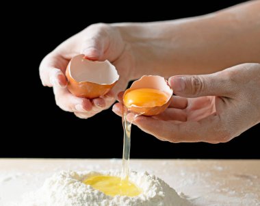 Siyah arka planda kırık bir yumurta ile el.