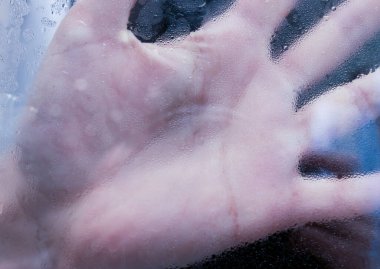Sis tutmuş soğuk bir penceredeki elin yansıması.