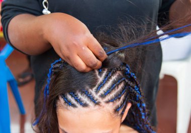 Kafasına ince örgüler örüyor.