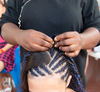 Kafasına ince örgüler örüyor.