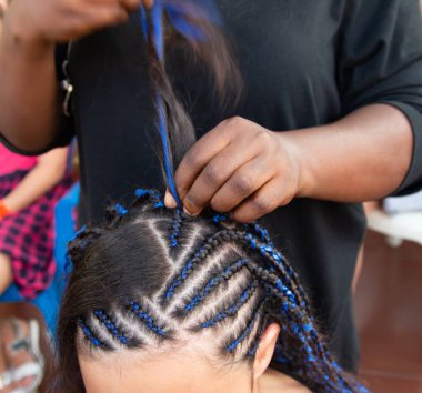 Kafasına ince örgüler örüyor.