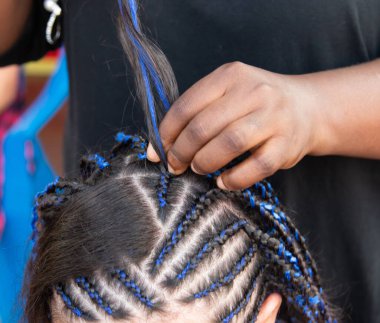 Kafasına ince örgüler örüyor.