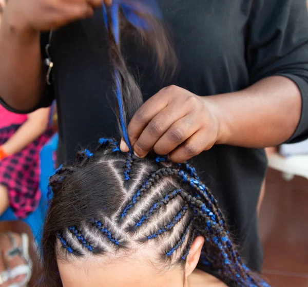 Kafasına ince örgüler örüyor.