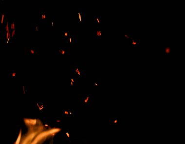 Siyah arkaplanda kıvılcımlar saçan bir ateş alevi