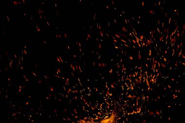 Siyah arkaplanda kıvılcımlar saçan bir ateş alevi