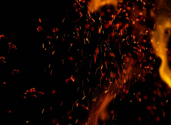 Siyah arkaplanda kıvılcımlar saçan bir ateş alevi