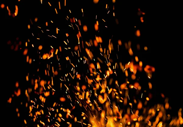 Siyah arkaplanda kıvılcımlar saçan bir ateş alevi